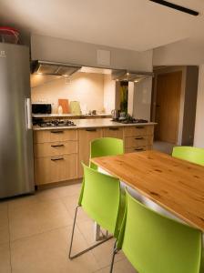 a kitchen with a wooden table and green chairs at Dom Winnica noclegi in Sochaczew