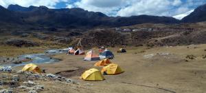 a group of tents pitched on a hill next to a river at Selena Camping in Tayapampa