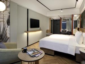 a hotel room with a large bed and a tv at Tribe Bali Kuta Beach in Kuta