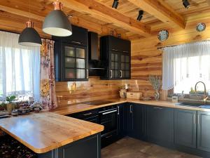 a kitchen with black cabinets and a wooden ceiling at Górska Chata w Górach Bystrzyckich in Niemojów