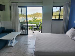 a bedroom with a bed and a balcony with a table at MSK Studios in Nydri