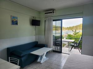 a living room with a couch and a table and a balcony at MSK Studios in Nydri