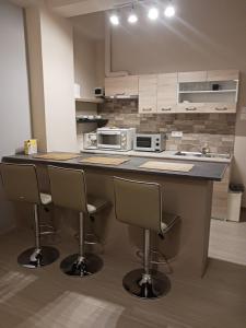 a kitchen with a counter with three bar stools at Cozy & modern apartment! in Kiaton