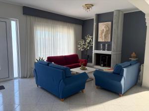 a living room with two blue chairs and a table at GianAngelo Holiday Villa in Kremasti