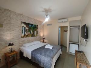 a bedroom with a bed and a flat screen tv at Pouso do parente in Pirenópolis