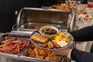 a person holding a plate of food in a buffet at Grand Caporal Hotel in Chiquimula