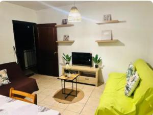 a living room with a couch and a tv at F2 Tahiti Lagoon Stays in Punaauia