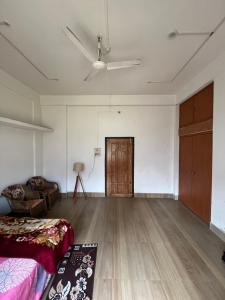 an empty living room with a couch and a ceiling fan at Kopou Homestay in Jorhat
