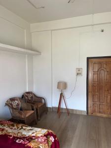 a room with a bed and a chair and a door at Kopou Homestay in Jorhat