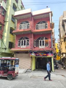a man walking in front of a red building at Hotel Lotus in kolkata
