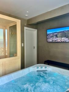 a large bath tub with a tv on the wall at Nayra View & Spa in Kavála