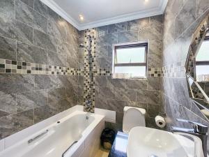 a bathroom with a tub and a sink and a toilet at Falcon Guest House in Harare +30 photos