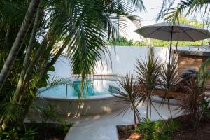 a swimming pool with an umbrella and palm trees at Casa Guadalupe - big beach oasis! in Brisas de Zicatela