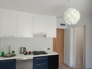 a kitchen with white cabinets and a sink and a chandelier at Azyl in Darłówko