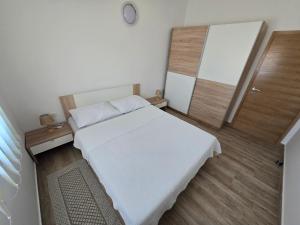 a small bedroom with a white bed and a mirror at Apartmani Kovač in Stara Novalja