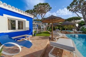 a blue house with a pool and chairs and umbrellas at Villa CHELSEA in Vilamoura