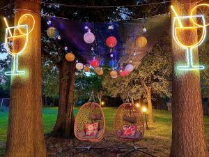 a couple of chairs sitting under two trees with lights at B&B La Borasca in Casalpusterlengo