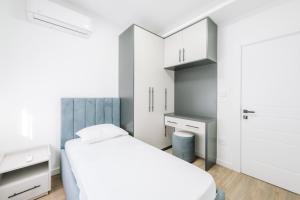 a white bedroom with a bed and a desk at Stanovic Bungalow in Ulcinj