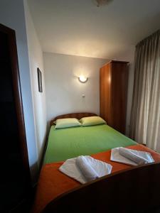 a bedroom with a green bed with towels on it at Villa primorka in Boreti