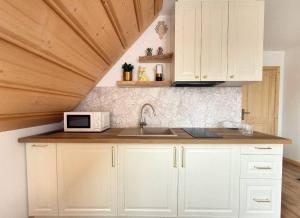 a kitchen with white cabinets and a microwave at Apartamenty 242E in Chochołów