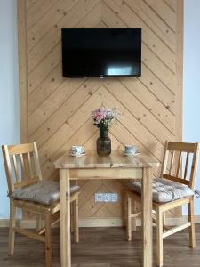 a wooden table with two chairs and a television on a wall at Apartamenty 242E in Chochołów +5 photos