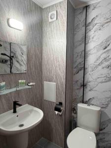 a bathroom with a white toilet and a sink at Family Hotel Trend in Ravda +40 photos