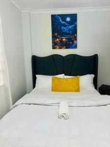 a bed with a black headboard and a yellow pillow at T-Homes in Thika