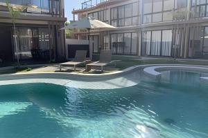 a swimming pool in front of a building with an umbrella at Condo with Beach Access By MME in Tatuamunha