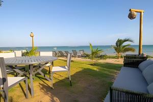 a patio with a table and chairs and the beach at Oka Milagres Beachfront Condominium By MME in Barra do Camaragibe