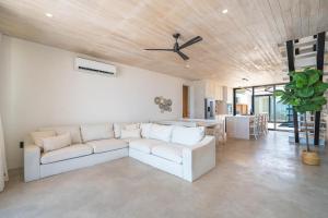 a living room with a white couch and a ceiling fan at LuxVilla Modern Beachfront in the Village in Caye Caulker