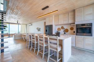 a kitchen with a bar with stools and a counter at LuxVilla Modern Beachfront in the Village in Caye Caulker