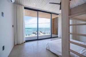 a bedroom with a bed and a view of the ocean at LuxVilla Modern Beachfront in the Village in Caye Caulker +37 photos