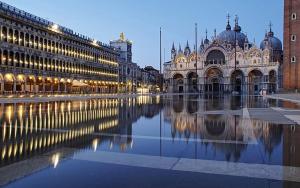 a large building with its reflection in the water at Venice Cappucina Guest House in Mestre