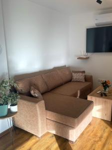 a living room with a brown couch and a flat screen tv at Vila Kraljica Une in Bosanska Krupa