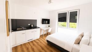 a white bedroom with a bed and a desk at StayIN Suites in Griesheim