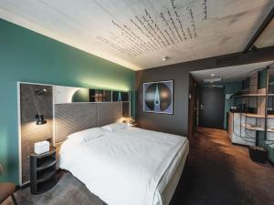 a bedroom with a large white bed and a ceiling at Mercure Hotel Delémont in Delémont