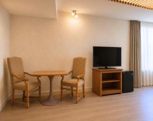 a room with a table and two chairs and a television at Hôtels Gouverneur Rimouski in Rimouski