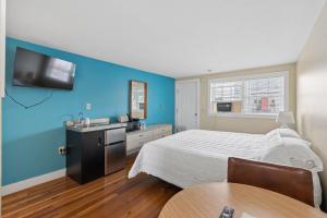 a bedroom with a bed and a tv on a blue wall at The Inn at Soho Square in Old Orchard Beach +22 photos