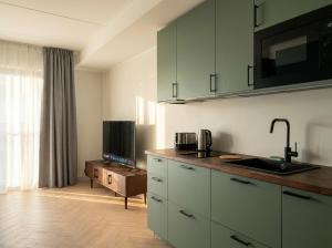 a kitchen with white cabinets and a sink and a tv at Oru Park & Sea Apartment in Tallinn