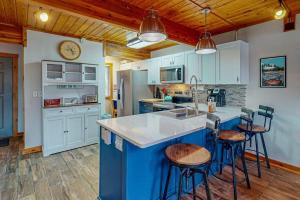 a kitchen with white cabinets and a blue island with bar stools at Sans Souci in McHenry