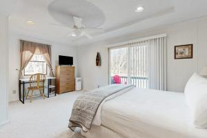 a white bedroom with a bed and a desk and a window at Nimba Cabin in Oakland +18 photos