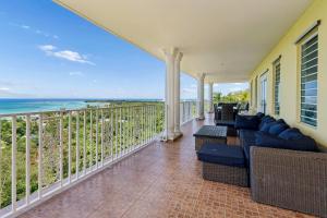 a balcony with a couch and chairs and the ocean at Villa del Enseuno- Pristine View and Infinity Pool in Luquillo