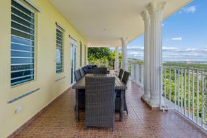 a porch with a table and chairs on a balcony at Villa del Enseuno- Pristine View and Infinity Pool in Luquillo