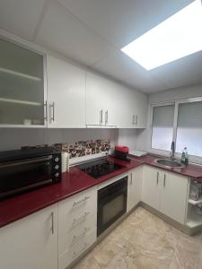 a kitchen with white cabinets and a red counter top at Veleta Montserrat - Alicante in Alicante
