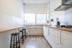 a kitchen with white cabinets and bar stools at D10 I shared bathrooms&kitchen in Garching bei München