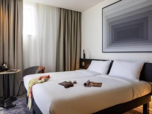 a hotel room with a large white bed with books on it at ibis Brussels Groot Bijgaarden in Groot-Bijgaarden
