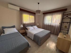 a bedroom with two beds and two windows at Olea House in Alexandroupoli