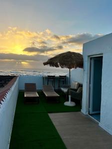 a patio with chairs and an umbrella and the ocean at El Cotillo Mar Beach in El Cotillo