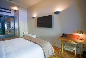a bedroom with a bed and a desk and a flat screen tv at Sela V Hotel in Brooklyn