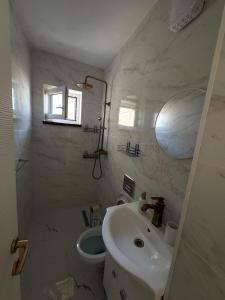 a white bathroom with a sink and a toilet at Apartament Deluxe in Orăştie